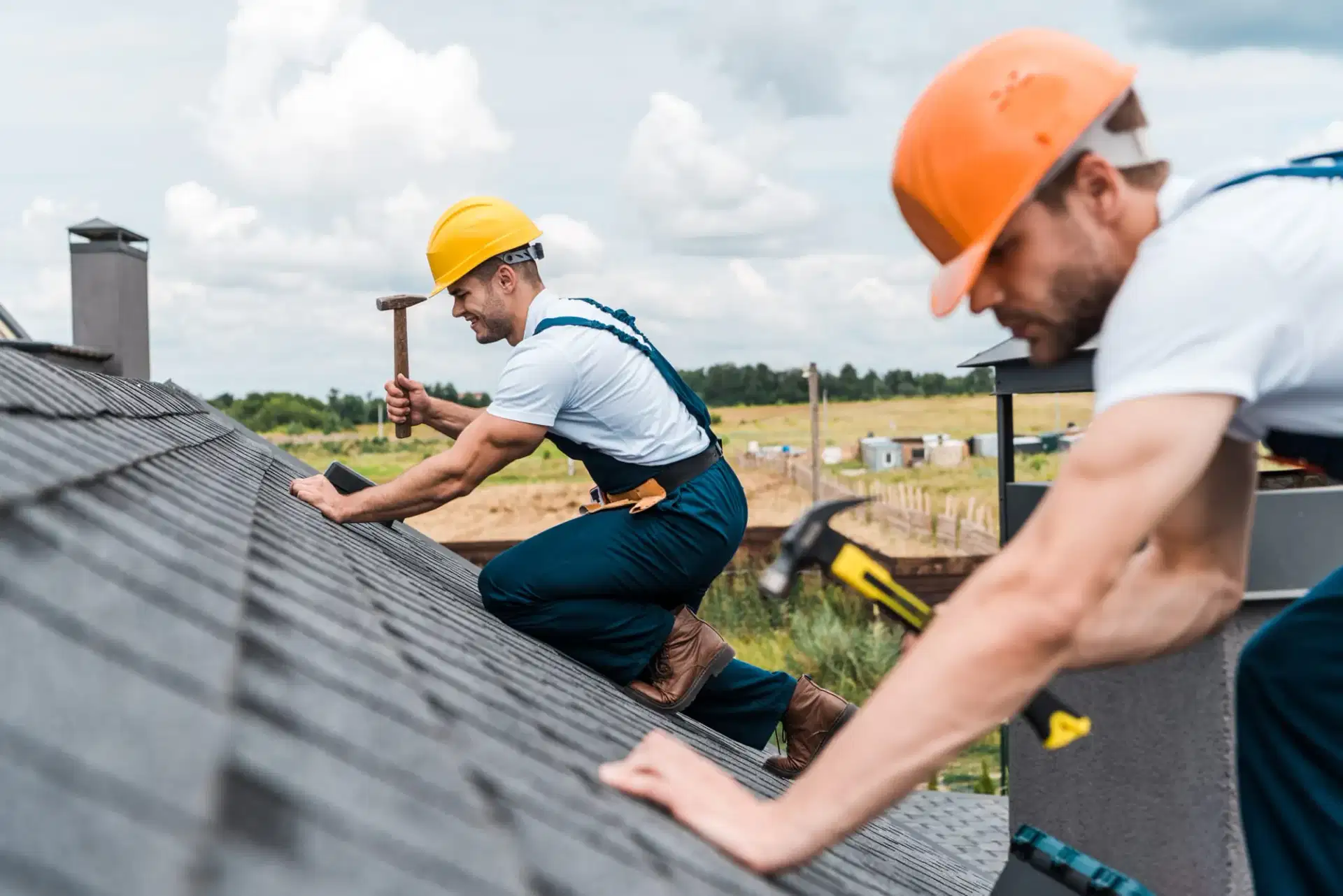 Roofers hammering asphalt shingles on a Suffolk County home