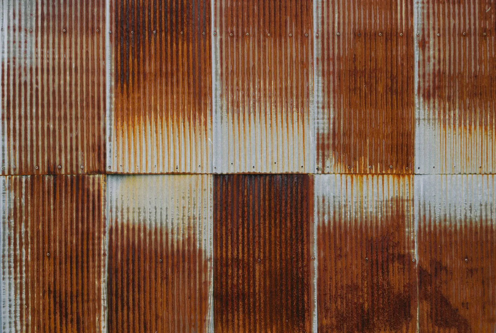 Corroded and rusted metal roof panels with exposed fasteners on a Port Jefferson, NY home