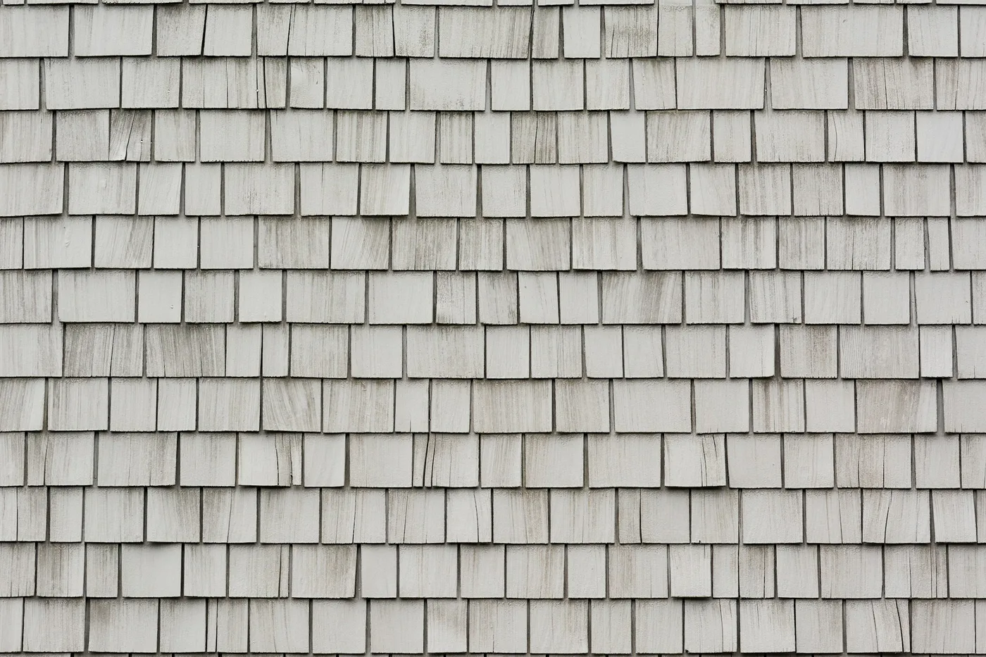 Close-up of cracked and worn gray asphalt roof shingles in need of repair