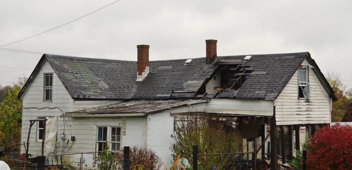 Suffolk County home with storm-damaged asphalt shingles and missing sections of roofing