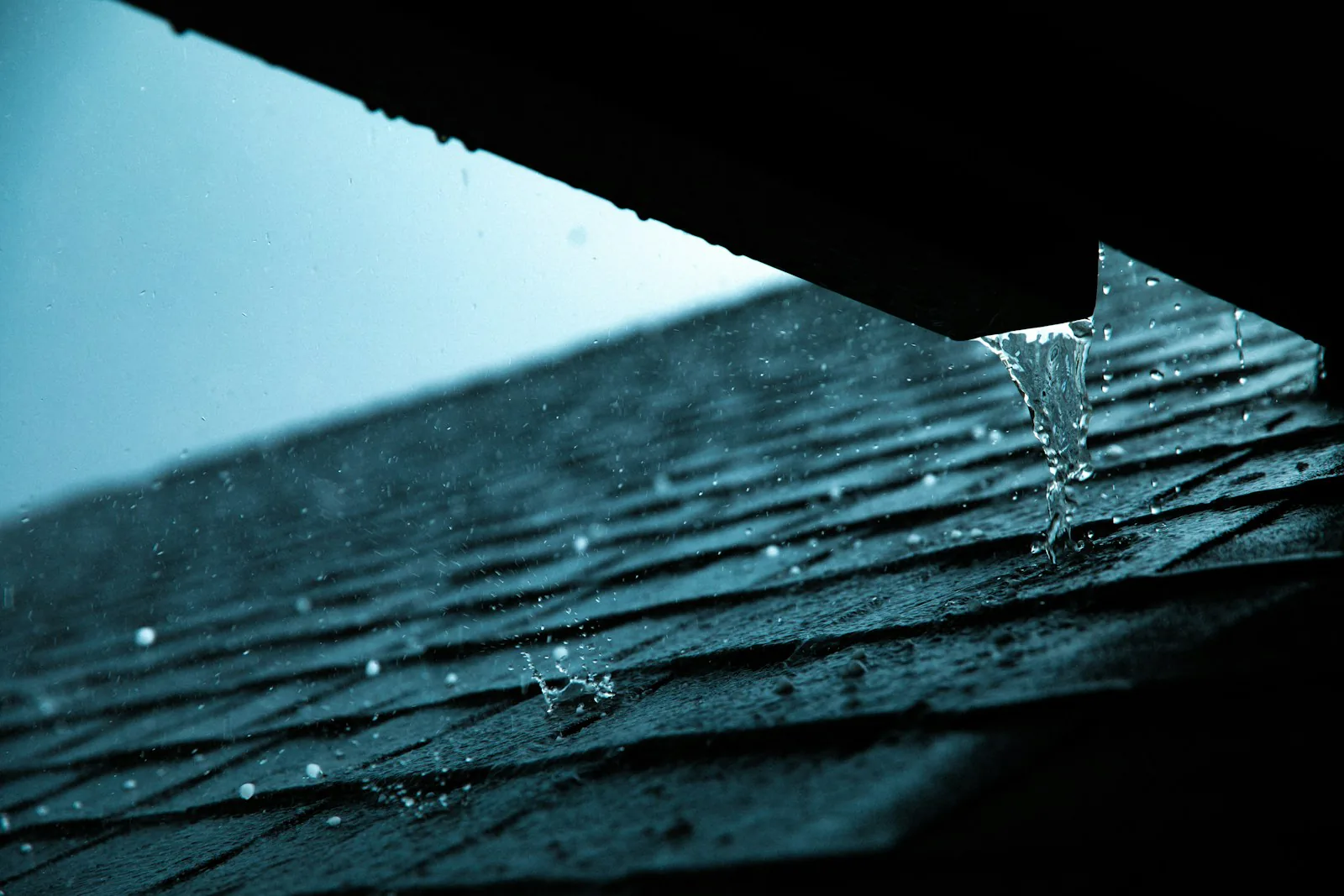 Heavy rain running off the shingle edge of a Commack, NY roof into the gutter line