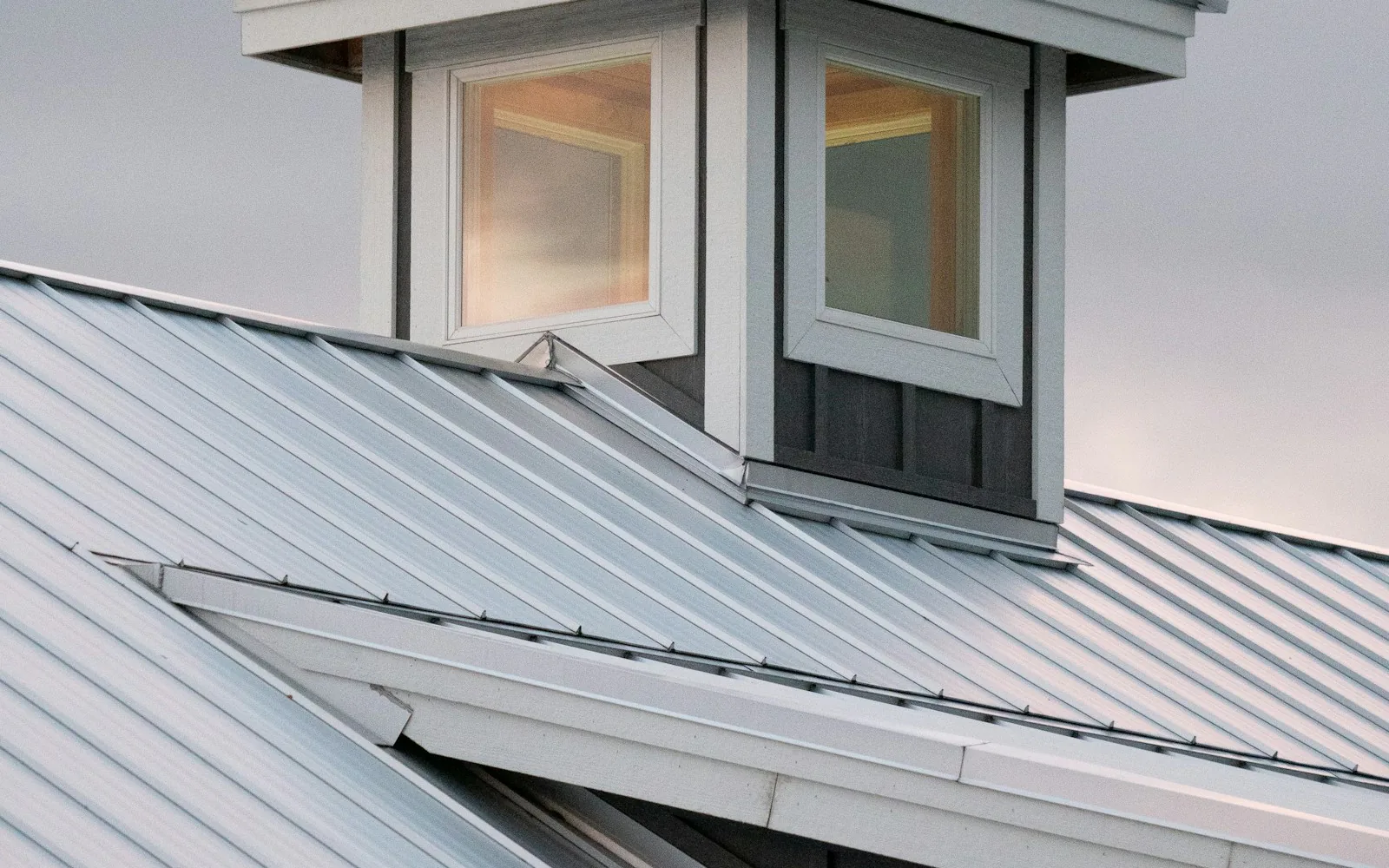 Standing seam metal roof showing sealed seams, ridge caps, and flashing transitions on a Port Jefferson, NY home