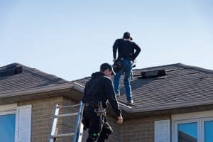 2 roofing professionals assessing a home